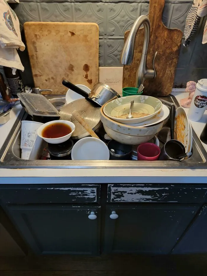 A kitchen sink overflowing with dirty dishes, showcasing the audacity some men bring into women's lives.