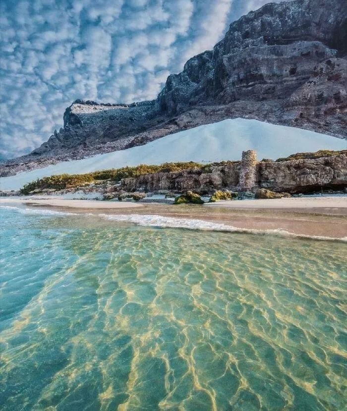 Real pictures of clear blue sea water under a rocky cliff