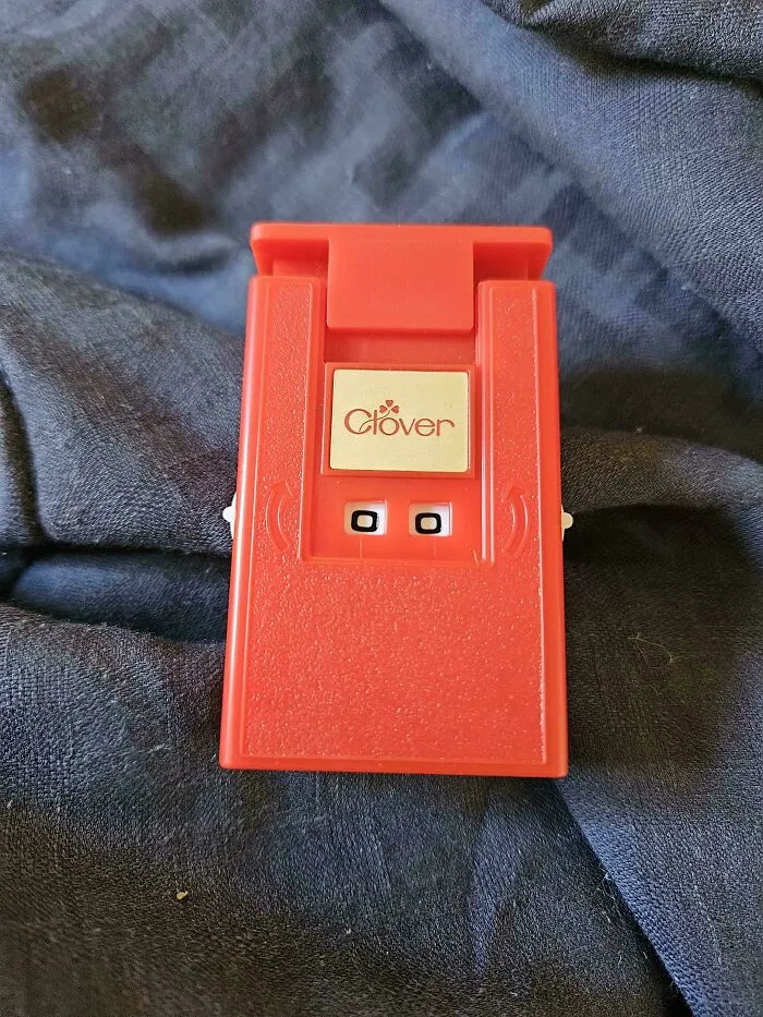 A small red Clover device sitting on a textured dark fabric.