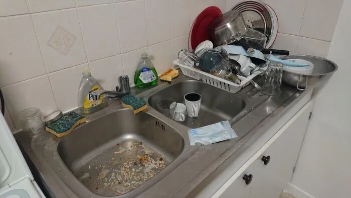 A kitchen sink piled high with dirty dishes highlighting unequal division of labor and audacity of some men