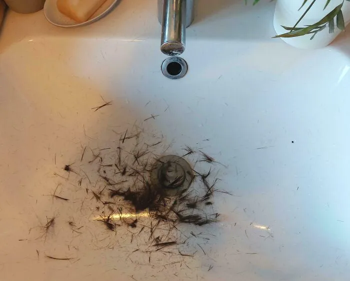 A bathroom sink covered in hair clippings after a haircut, showcasing the audacity of some men.