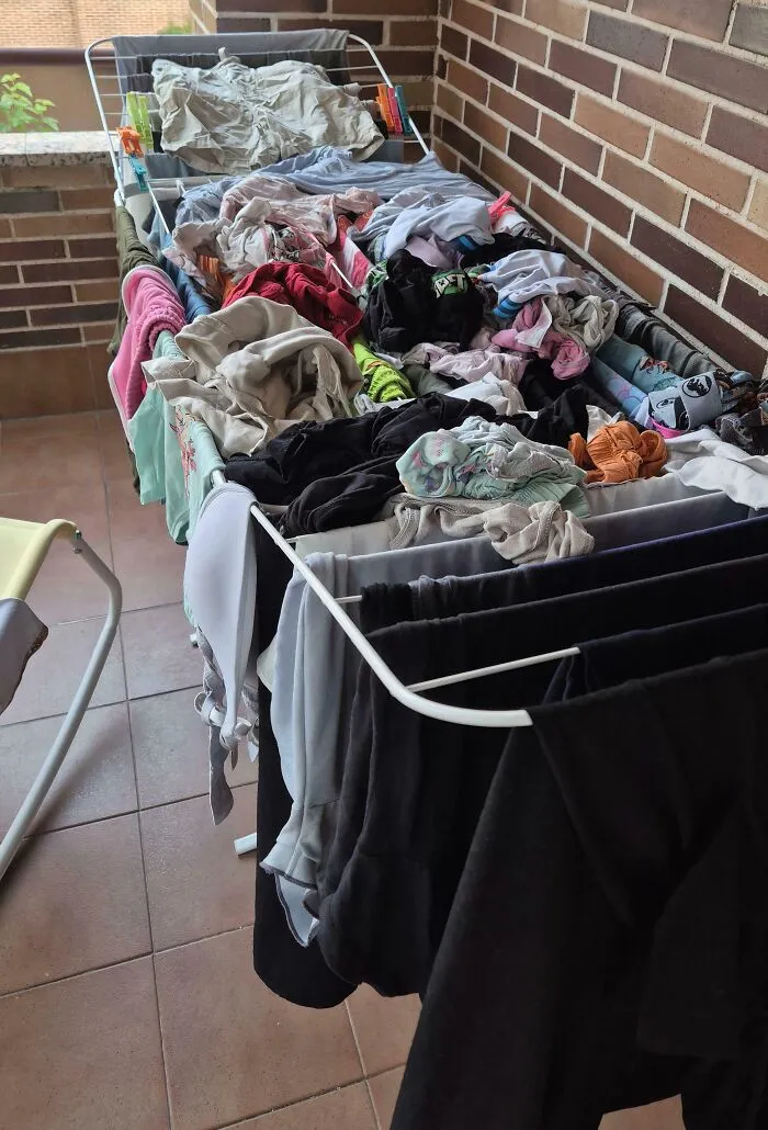 A drying rack overflowing with a chaotic pile of damp clothes, representing sheer audacity in housekeeping