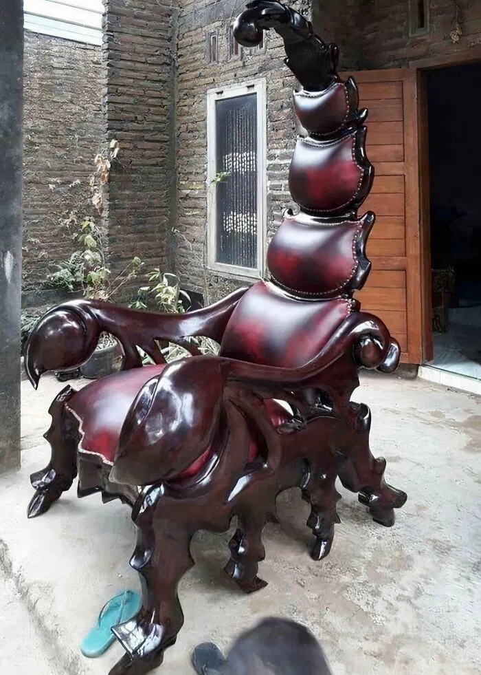 An elaborate scorpion shaped armchair crafted from dark wood and red leather, showcasing a bold design vision