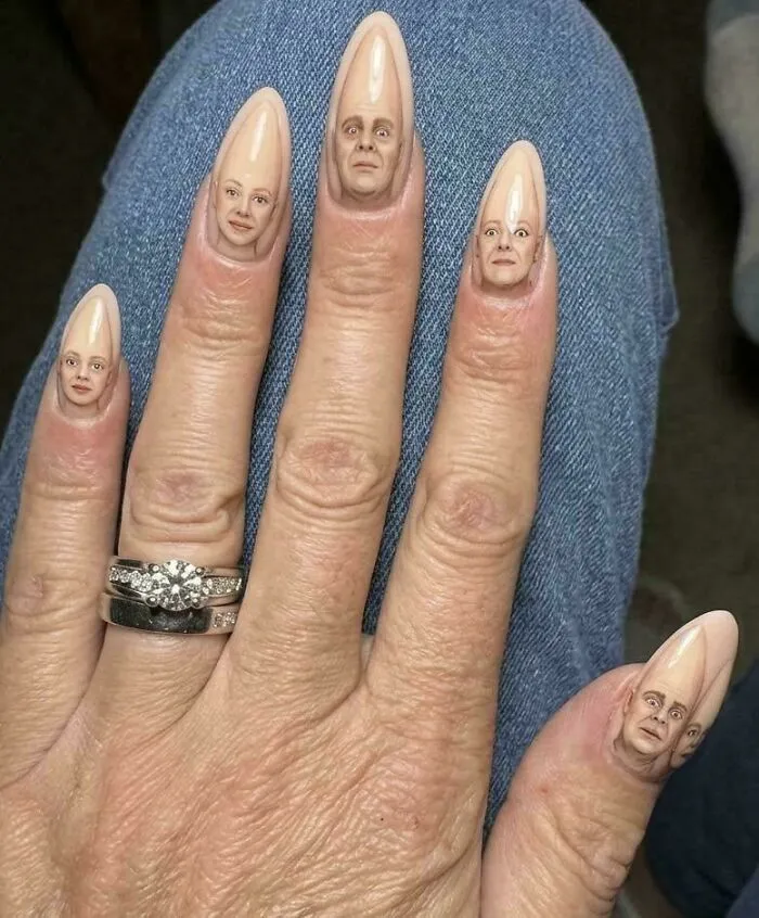 Stiletto fingernails decorated with realistic faces, showing creations awful to look at but far too well made.