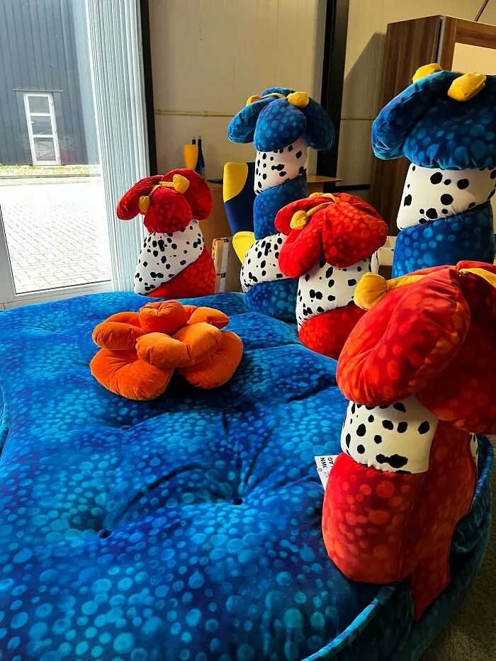 A blue plush couch decorated with colorful mushroom-like pillows, an example of creations awful to look at but well made.