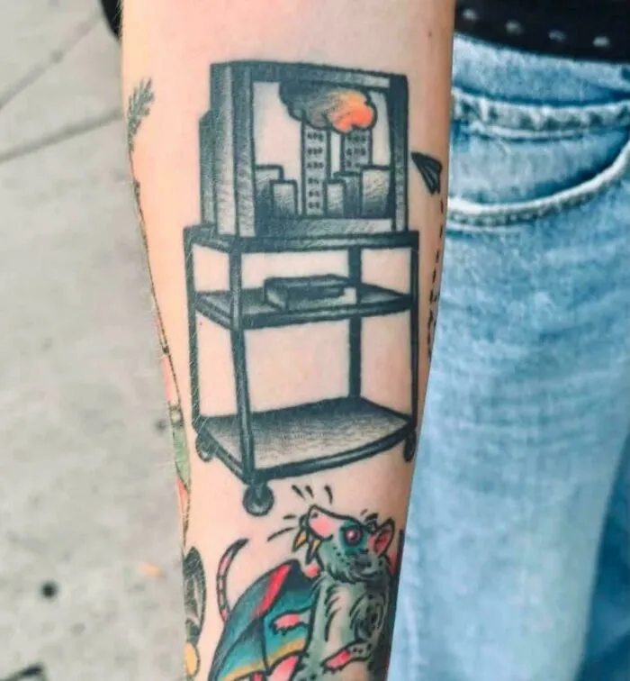 Tattoo of a rolling TV cart displaying a news broadcast, featured among creations awful to look at.