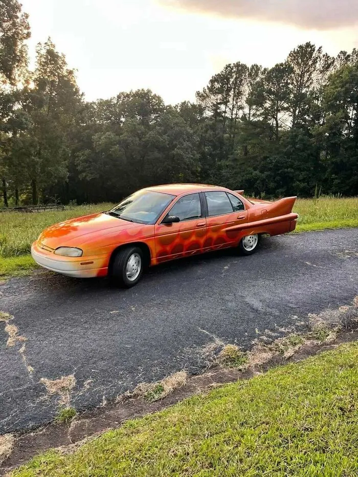Custom orange painted car with rear fins parked outside, among creations awful to look at but well-made.