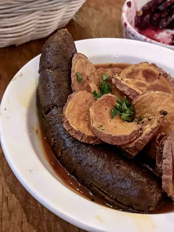 Dark sausage with sliced potatoes served in broth, showcasing questionable food combos.
