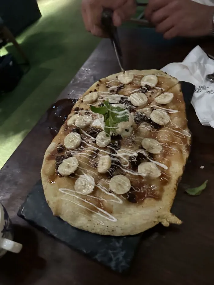 A dessert flatbread topped with sliced bananas and sweet drizzle, a creative twist on food combinations