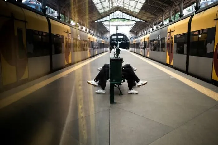 A street photographer captures a reflection of a train station, creating a symmetrical, coincidental scene.