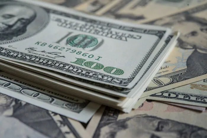 A close-up stack of 100 US dollar bills, representing financial aspects linked to marriage regrets