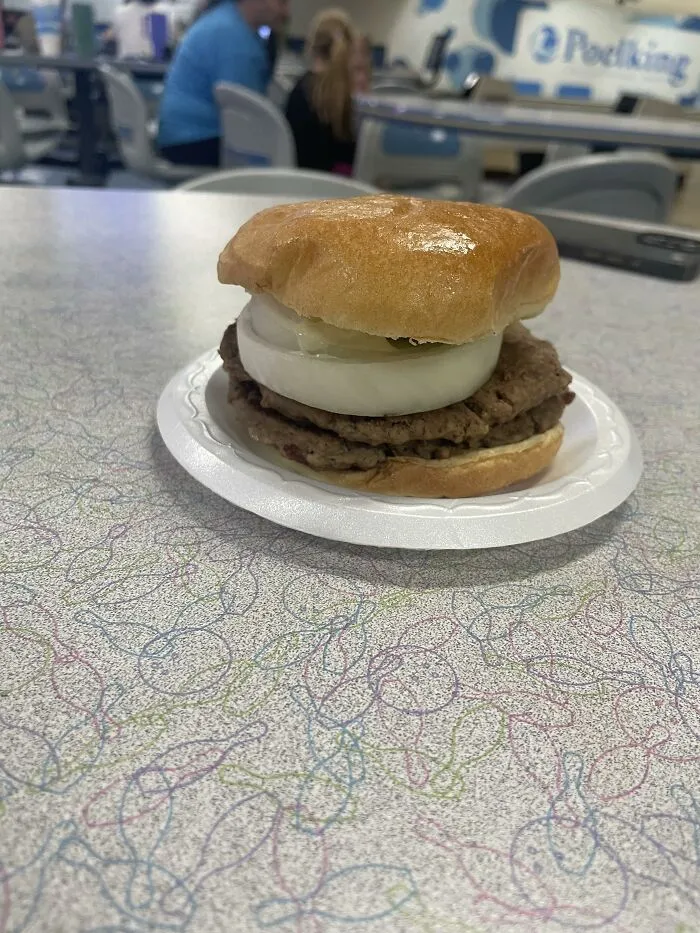 A double patty hamburger topped with a massive thick slice of raw white onion, showing food combinations
