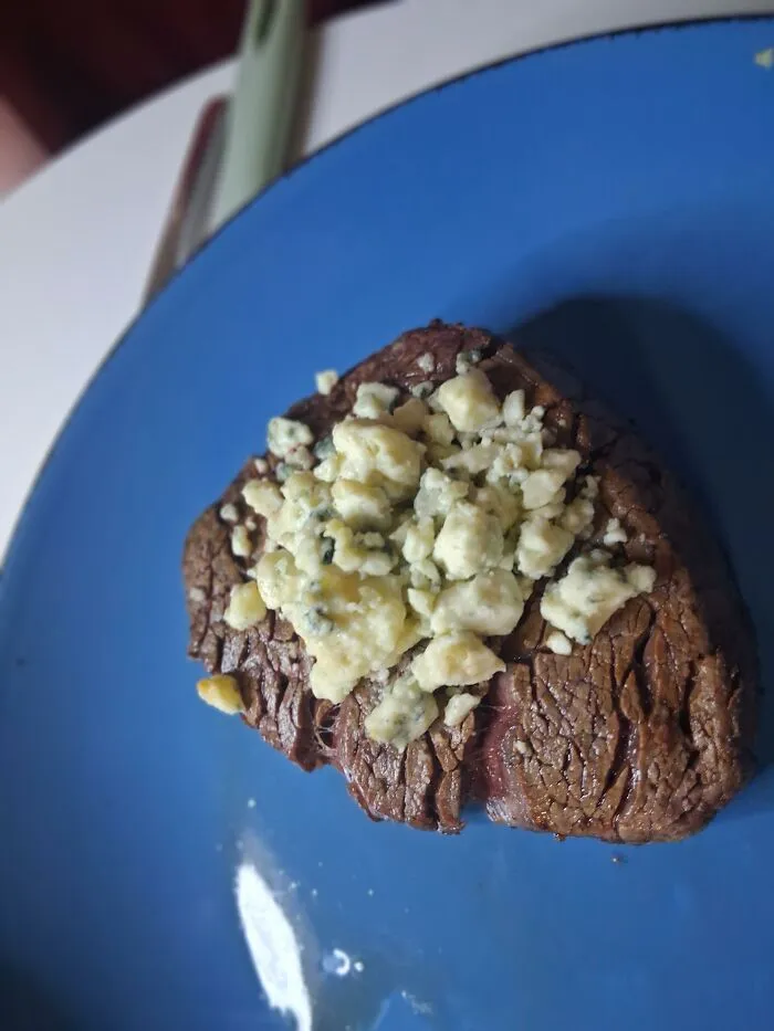 A grilled steak topped with crumbled blue cheese, representing weird food combinations.