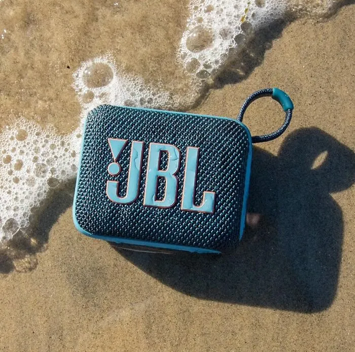 A blue JBL waterproof speaker sitting on the sand, a find from Prime Big Deal Days.
