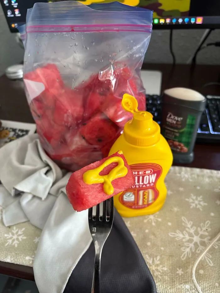 Unusual food combinations of a watermelon cube topped with yellow mustard on a fork