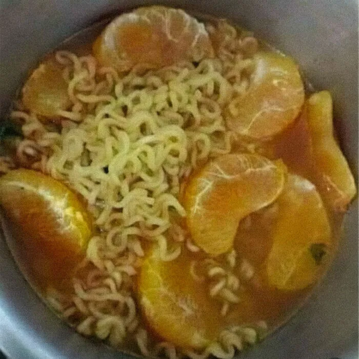 Strange food combinations with ramen noodles topped with orange slices in a pot