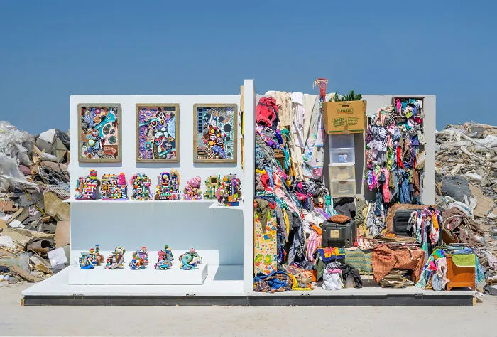 An art installation combining colorful framed mosaics and piles of discarded clothes as unusual sculptures