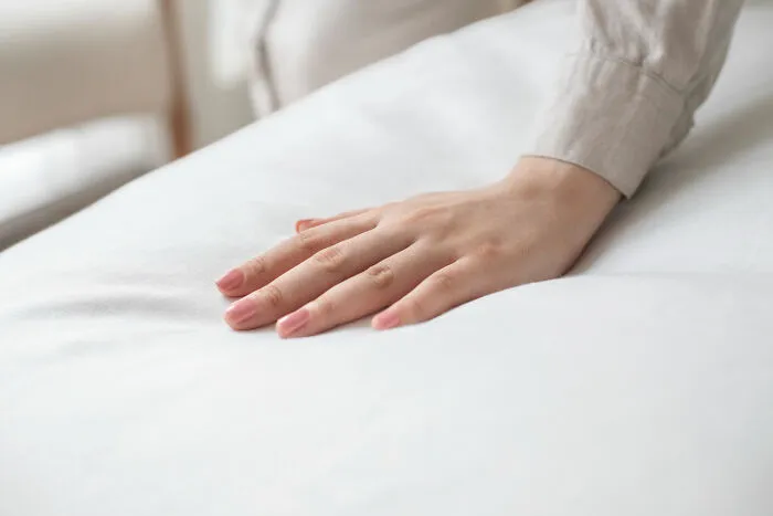 A hand resting gently on a soft white mattress, symbolizing comfort from ridiculous arguments.