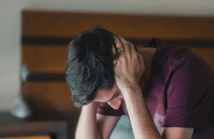 A man holding his head in distress, representing the headaches and struggles men face in relationships.