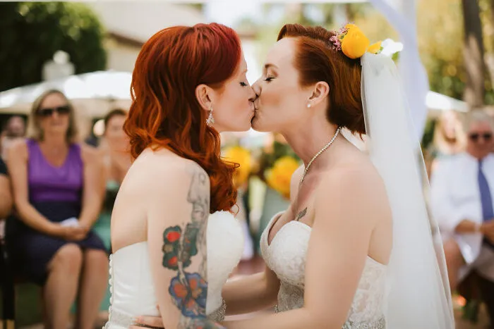 Two brides with red hair kissing during their wedding ceremony