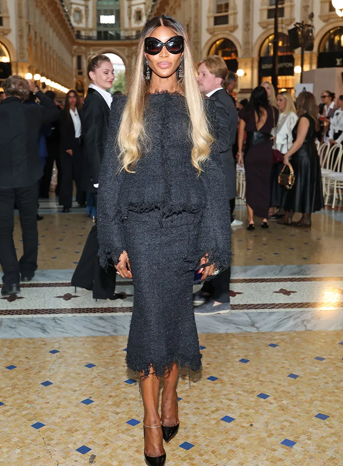 Woman in black textured dress and sunglasses at Plastic Surgery Expo fashion event