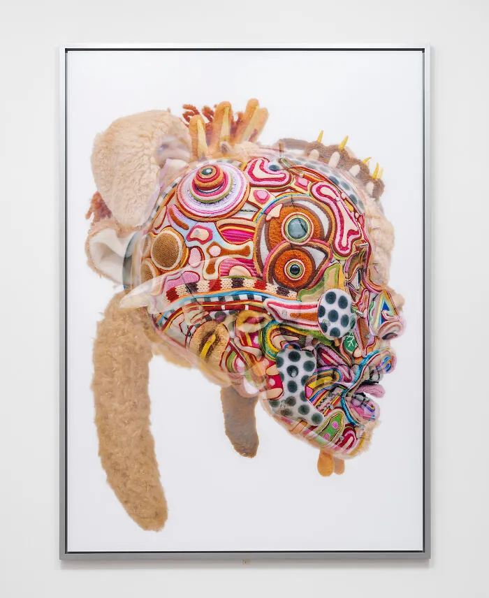 A detailed close-up of unusual sculptures showing a colorful face made of yarn and plush fabric