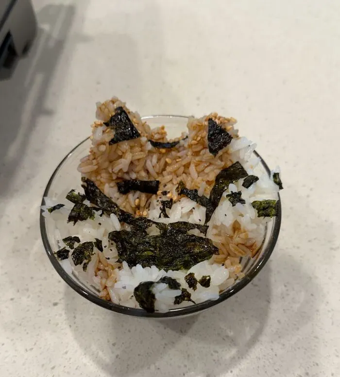 White and brown rice with seaweed strips shaped like a cat, a cute but unusual food combination