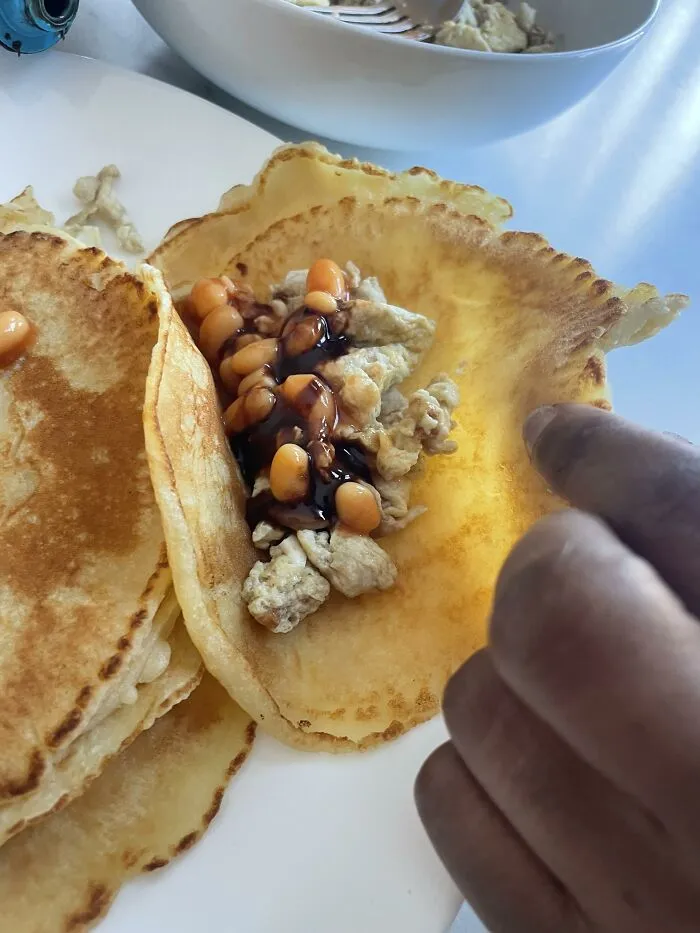 A pancake filled with scrambled eggs and baked beans as a strange food combination