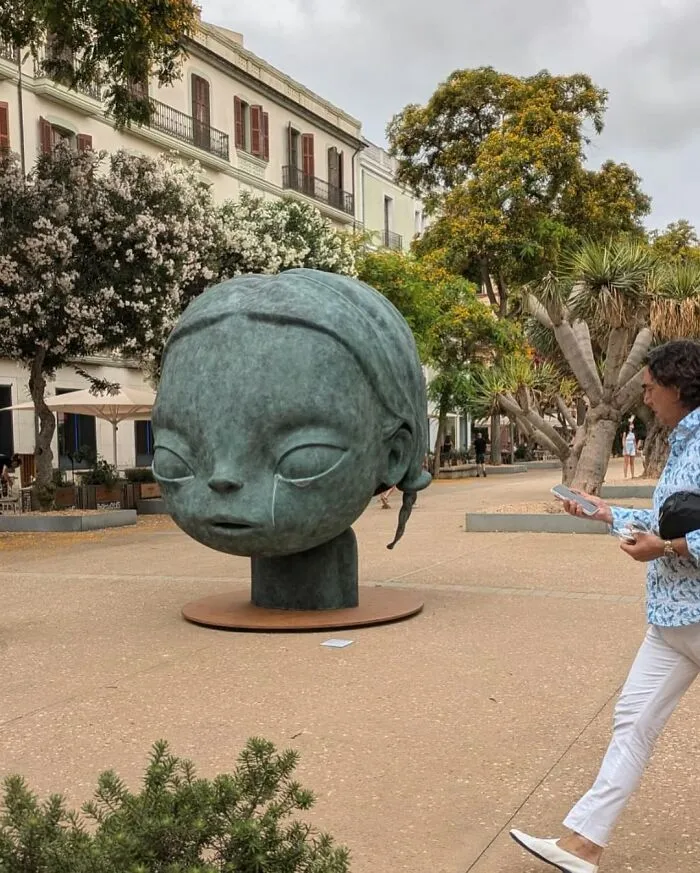 A large, modern sculpture of a child's head, an example of stunning street art in an urban square.