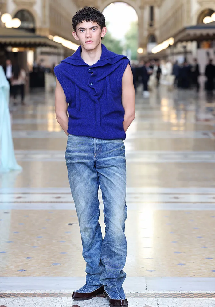 Male model wearing blue sleeveless top and jeans at Plastic Surgery Expo fashion event