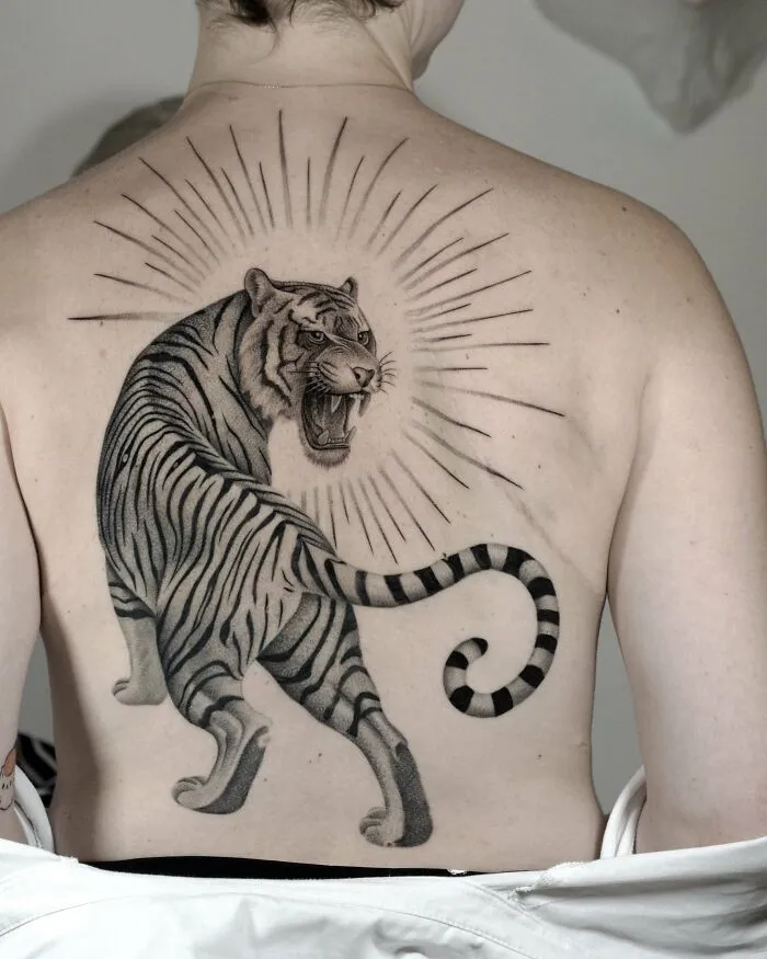 Realistic tiger tattoo with glowing rays on upper back nature ink tattoo