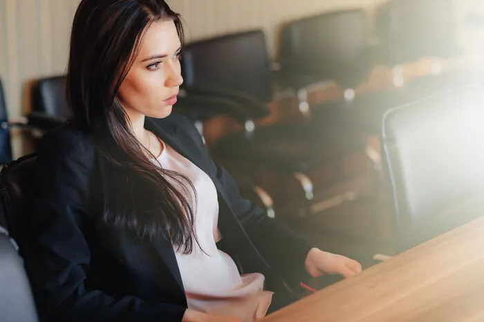 A thoughtful female lawyer in a meeting room, reflecting on cases where clients behaved stupidly with the cops.
