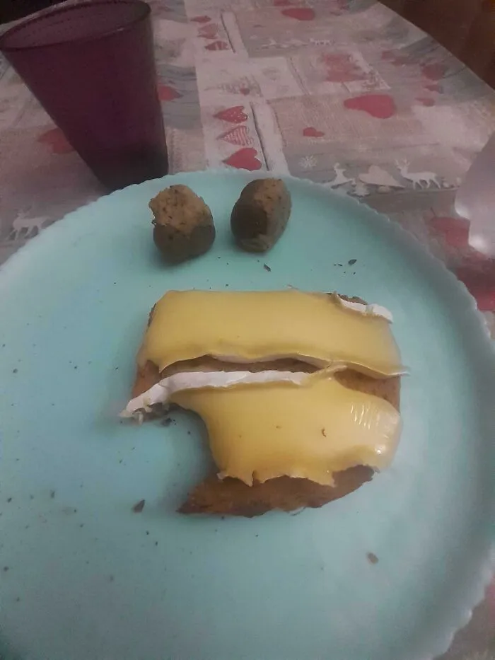 Odd food combinations with melted processed cheese over toast and two chocolate balls on a blue plate