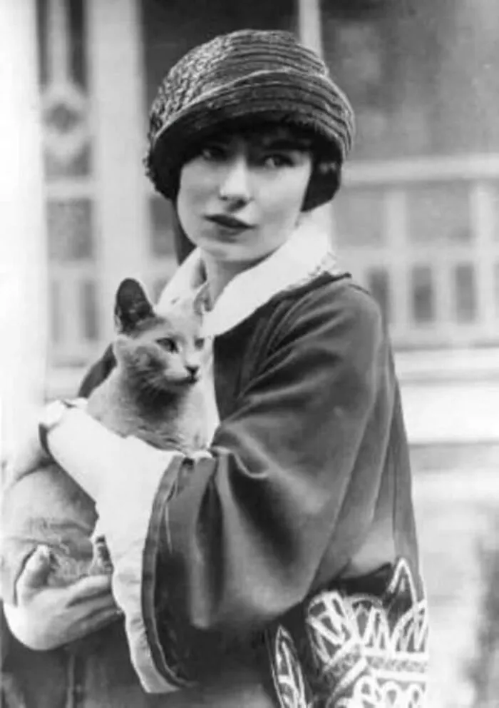 A stylish woman wearing a cloche hat cradling her feline friend in vintage cat photos