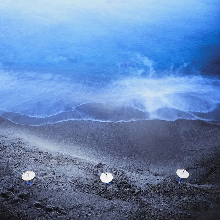 Blue and black film photograph of beach shoreline with abstract lighting effects