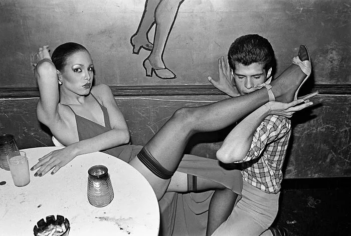 Black and white analog film photography capturing dramatic pose at a bar scene