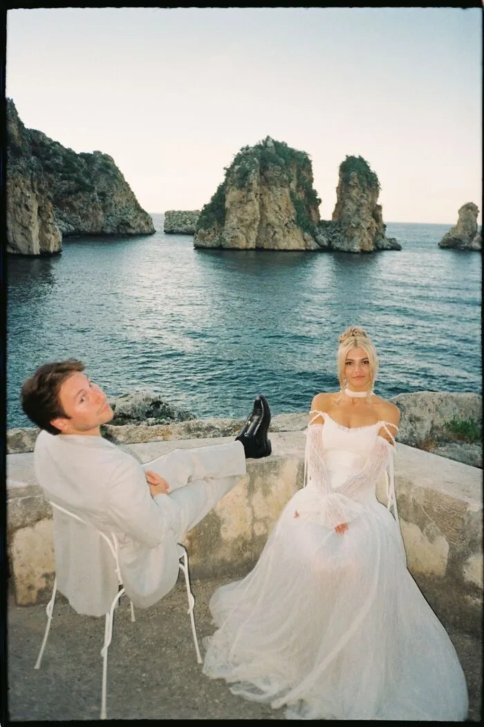 Analog film photo of couple by rocky coastline with sea and rock formations in background