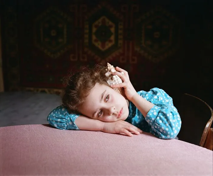Portrait of girl listening to shell in nostalgic analog film photography
