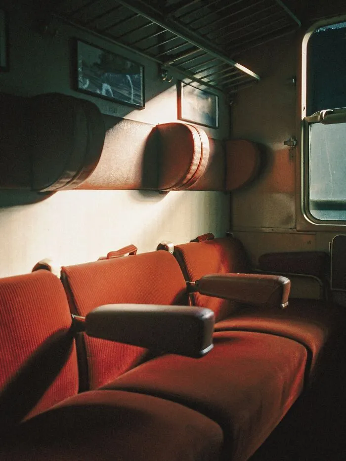 Analog film photo of red seats inside a vintage train car with soft lighting