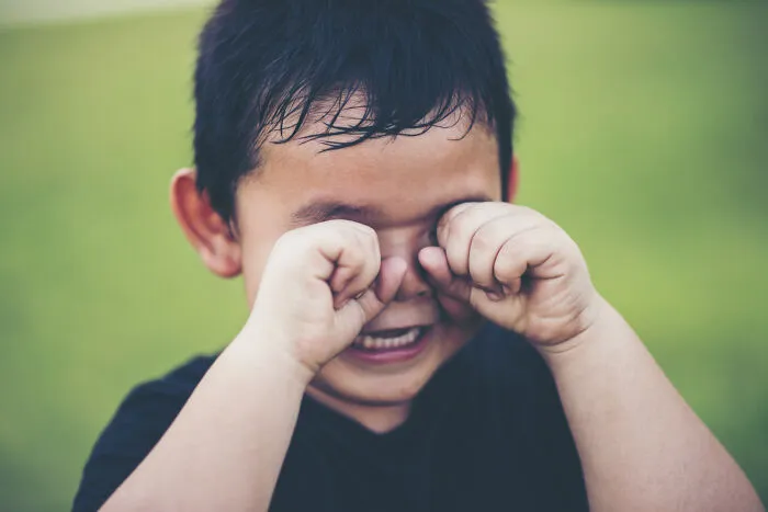 Young child rubbing eyes and crying, showing how strange patients express discomfort.