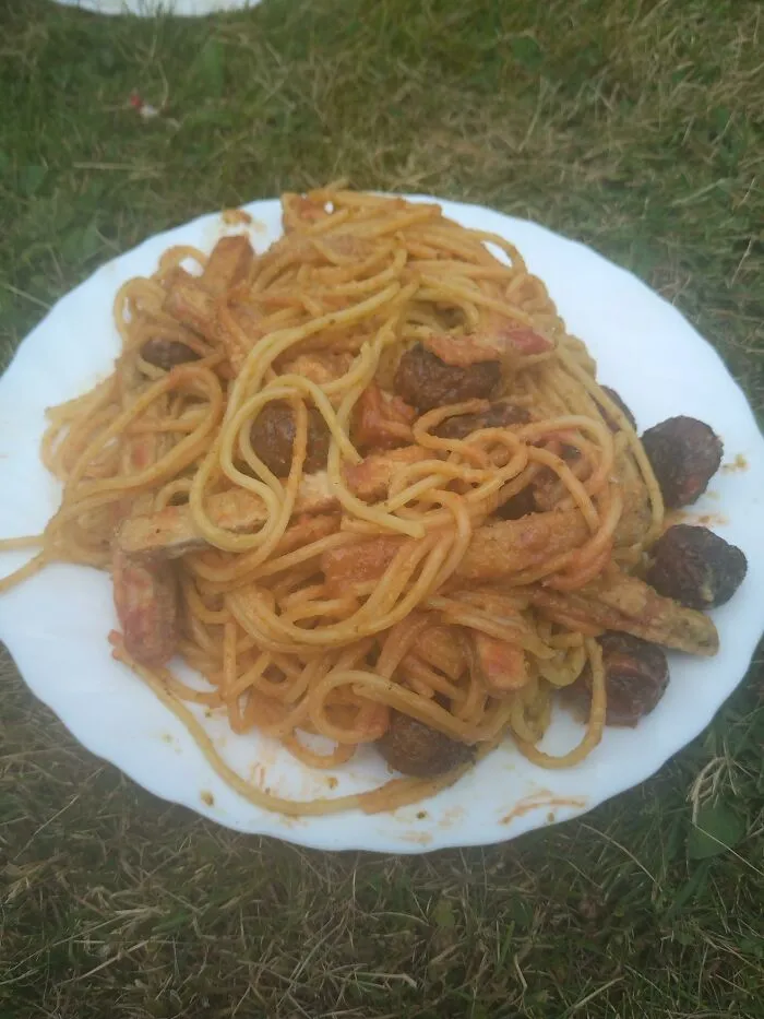 A plate of spaghetti mixed with meatballs and French fries, illustrating odd food combinations