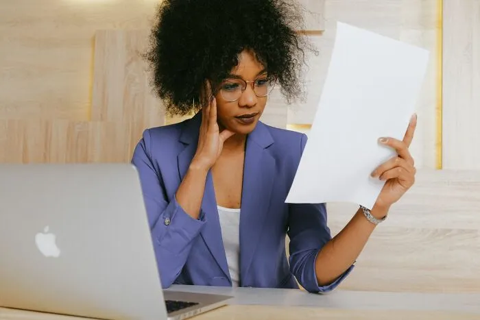 A teacher looking perplexed at a document in class, wondering about a student's lack of common sense