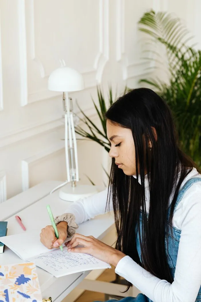 A female student writing in her notebook during a class, relating to teachers recall of students