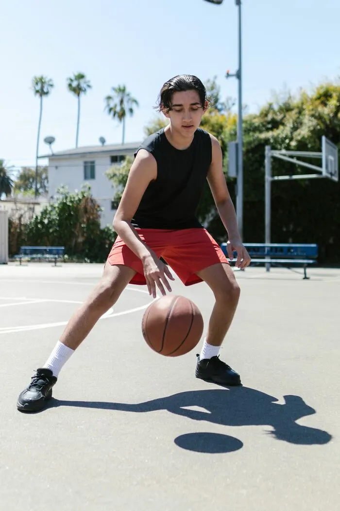 A young male student playing basketball outside, showcasing teachers recall the students active moments