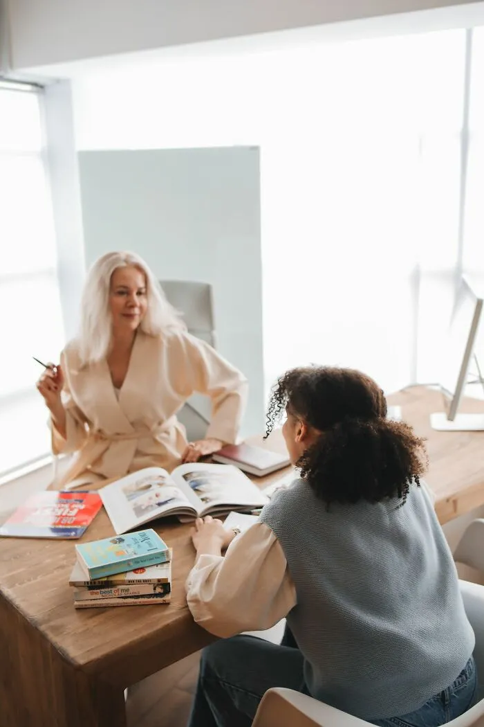 A teacher mentoring a student at a desk, a scene where teachers recall classroom moments