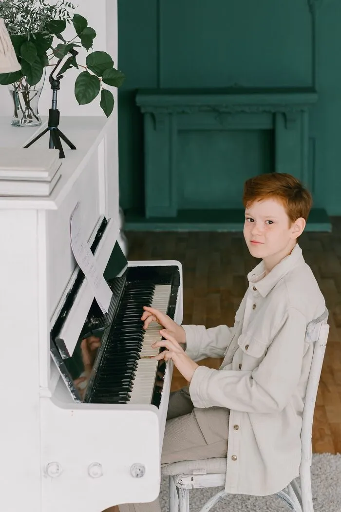 A young student playing a white piano, demonstrating talent in class