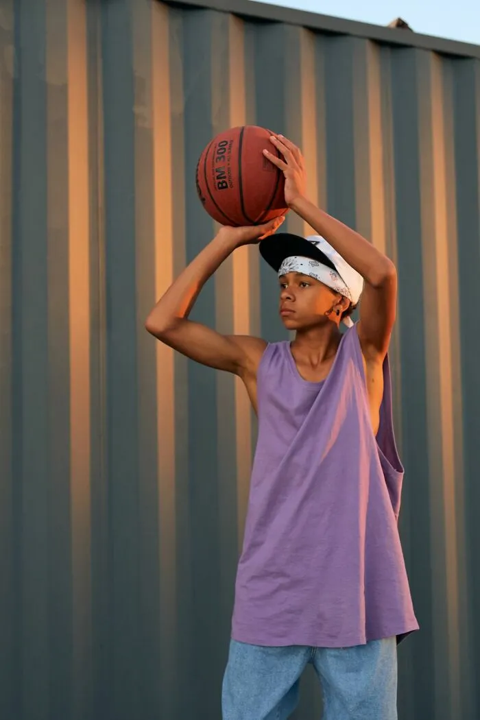 A teenager preparing to shoot a basketball, showing a need for common sense in class sports