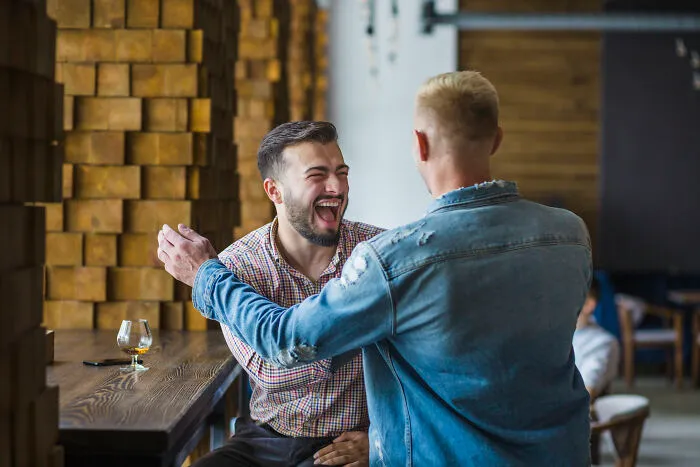 Two men greeting each other with laughter, relating to stories of divorced people