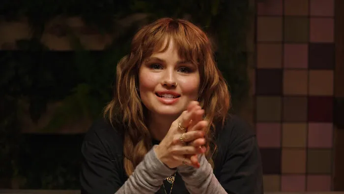Debby Ryan smiling and holding her hands together, discussing celebrity encounters.