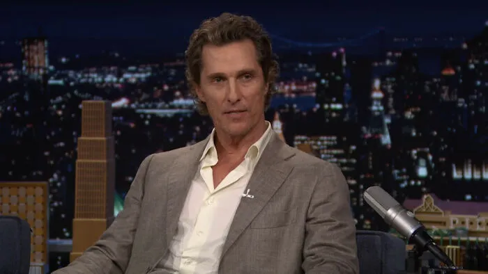 Matthew McConaughey in a suit on a talk show discussing celebrity encounters